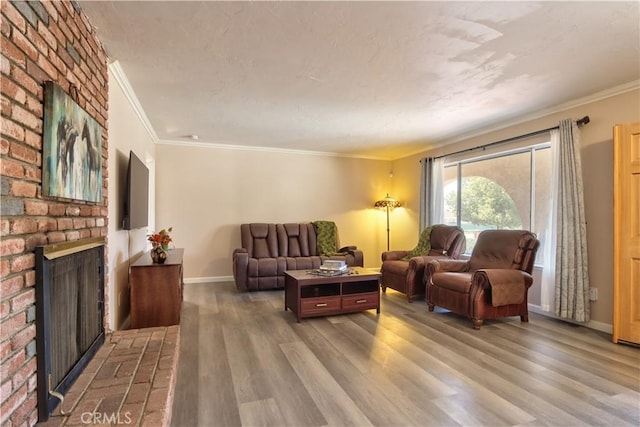 living area featuring ornamental molding, a brick fireplace, wood finished floors, and baseboards