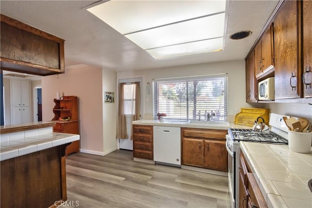 25602 Malaga Rd, Menifee, CA 92585 - kitchen featuring white appliances, tile counters, a sink, light wood-style flooring, and baseboards