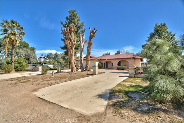 view of front facade featuring fence, concrete driveway, and stucco siding