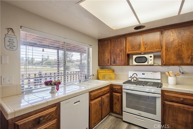 25602 Malaga Rd, Menifee, CA 92585 - kitchen featuring white appliances, a sink, light wood-style floors, tile counters, and brown cabinetry