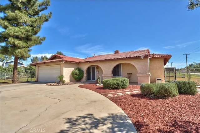 mediterranean / spanish-style house with a garage, a tile roof, concrete driveway, and stucco siding