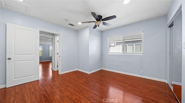 unfurnished bedroom featuring attic access, wood finished floors, visible vents, and baseboards