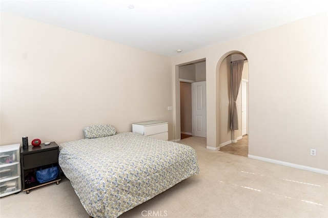 bedroom featuring arched walkways, carpet floors, and baseboards