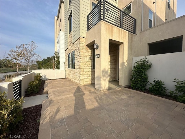 view of patio featuring fence and a balcony