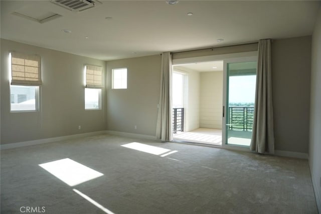 empty room featuring carpet floors, plenty of natural light, visible vents, and baseboards