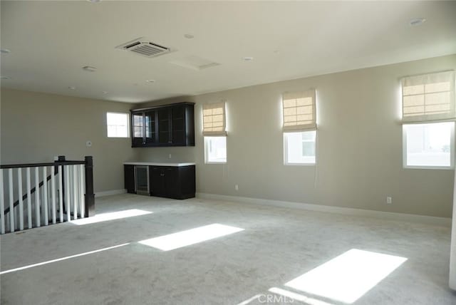 spare room featuring baseboards, visible vents, and light colored carpet