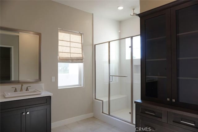 bathroom with a stall shower, vanity, and baseboards