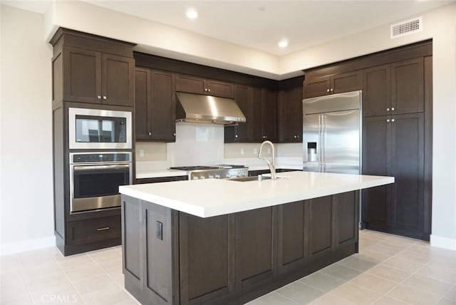 kitchen featuring visible vents, built in appliances, light countertops, under cabinet range hood, and a sink