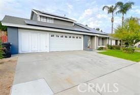 traditional-style house with a garage, roof mounted solar panels, and concrete driveway