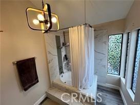 full bath with baseboards, shower / tub combo with curtain, and wood finished floors