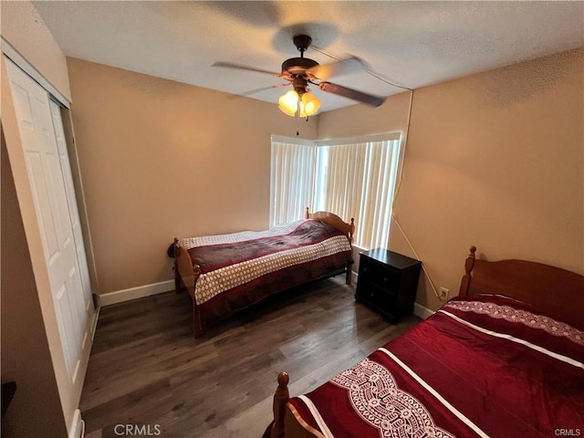 bedroom featuring a ceiling fan, a closet, baseboards, and wood finished floors