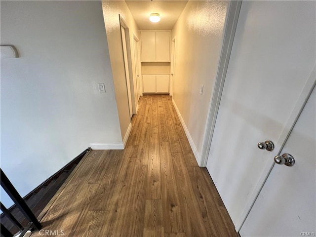 hallway featuring wood finished floors and baseboards