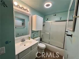 full bathroom featuring toilet, enclosed tub / shower combo, and vanity