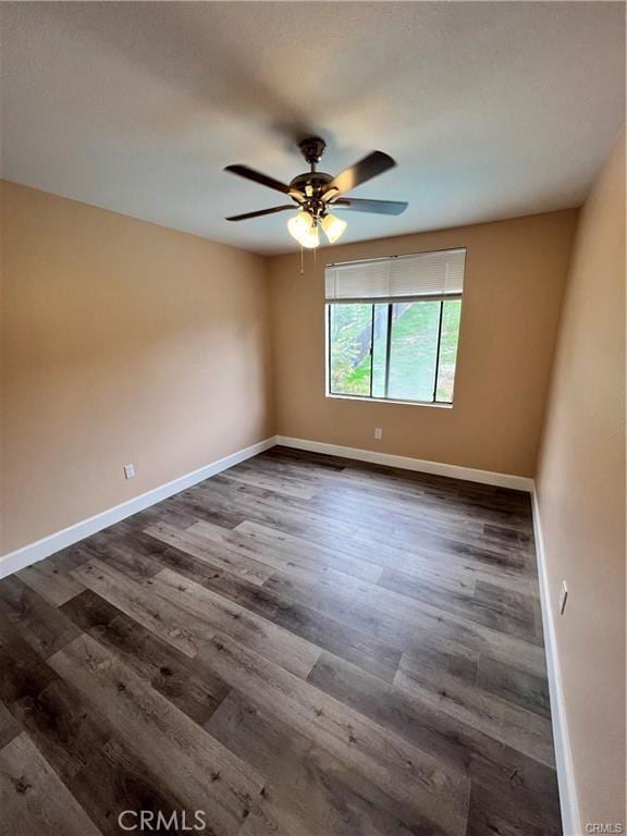 unfurnished room with ceiling fan, baseboards, and dark wood finished floors