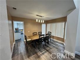 dining space with wood finished floors, visible vents, and baseboards