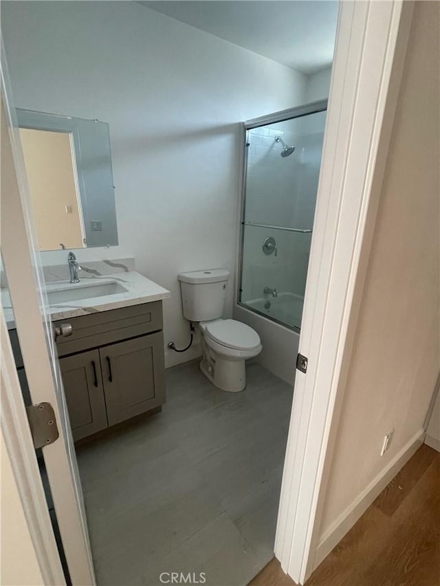 bathroom featuring enclosed tub / shower combo, vanity, toilet, and wood finished floors