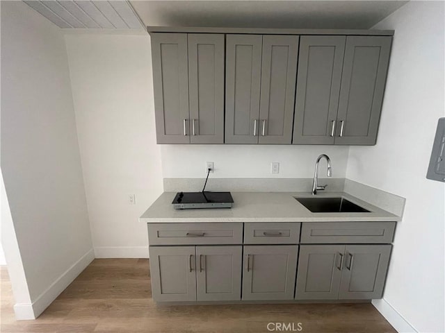 kitchen with light countertops, a sink, and gray cabinetry