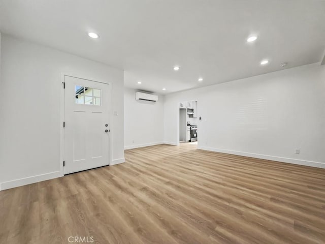 entryway featuring a wall unit AC, light wood-type flooring, baseboards, and recessed lighting