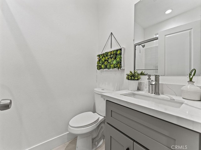 full bathroom with baseboards, vanity, toilet, and a shower with door