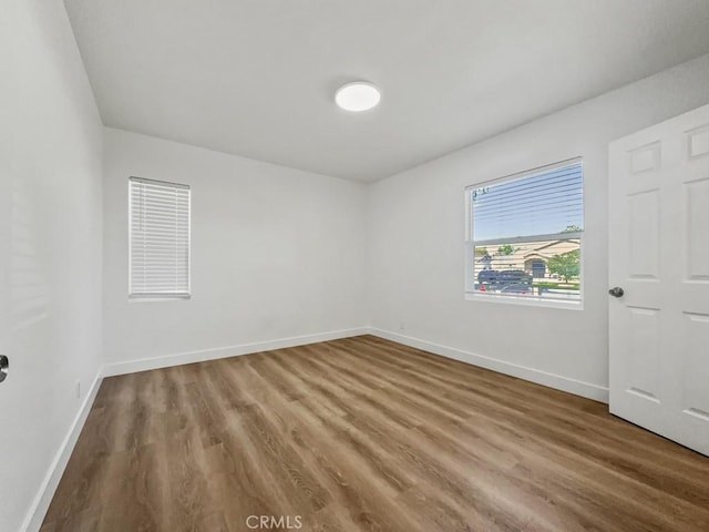 spare room featuring baseboards and wood finished floors