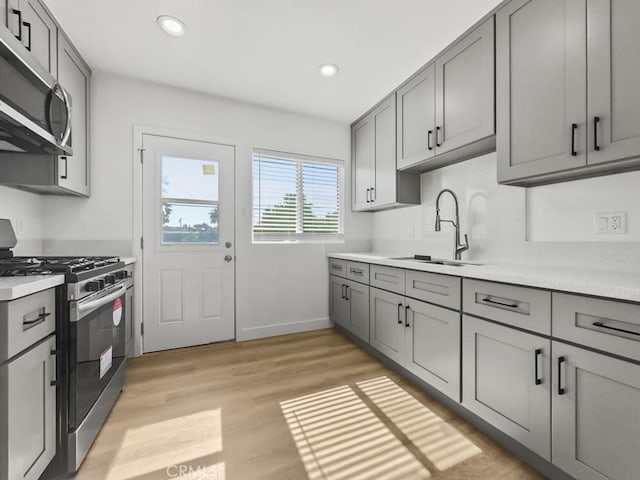 kitchen with light wood-style flooring, appliances with stainless steel finishes, light countertops, gray cabinetry, and recessed lighting