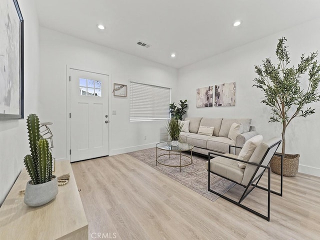 living room featuring recessed lighting, baseboards, and light wood finished floors