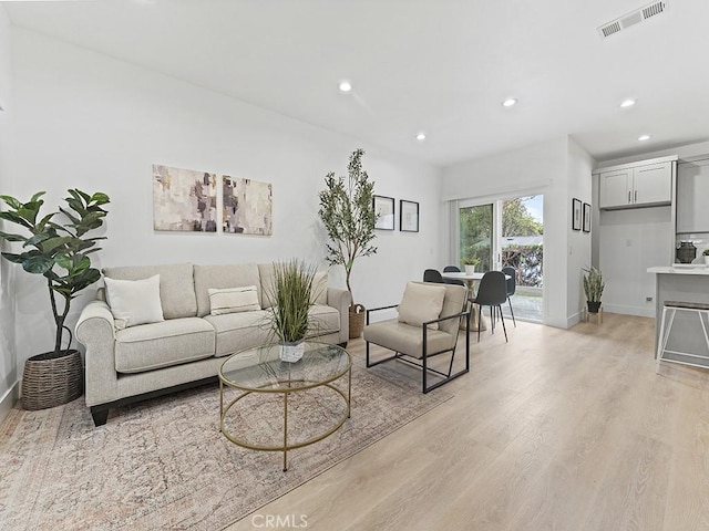 living area with light wood-style floors, recessed lighting, visible vents, and baseboards