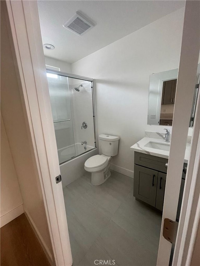 bathroom with baseboards, visible vents, toilet, combined bath / shower with glass door, and vanity