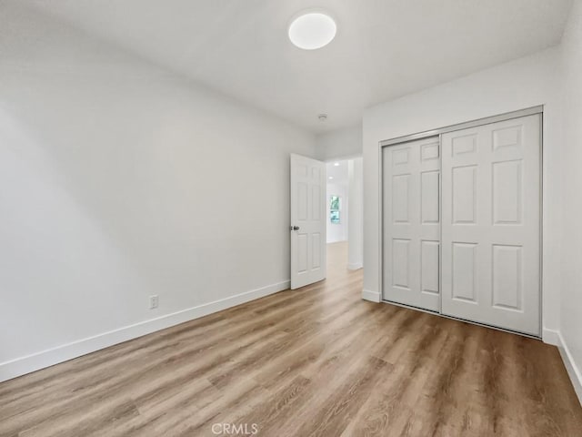 unfurnished bedroom with a closet, baseboards, and wood finished floors