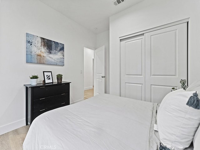 bedroom with visible vents, a closet, baseboards, and wood finished floors