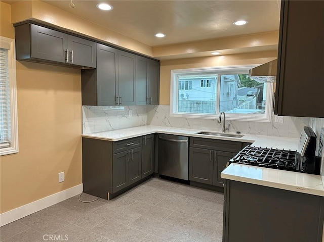 kitchen with baseboards, dishwasher, backsplash, light countertops, and a sink