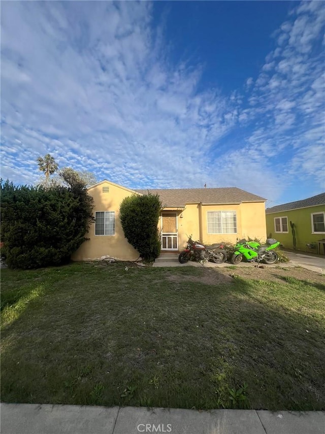 ranch-style home with a front lawn and stucco siding