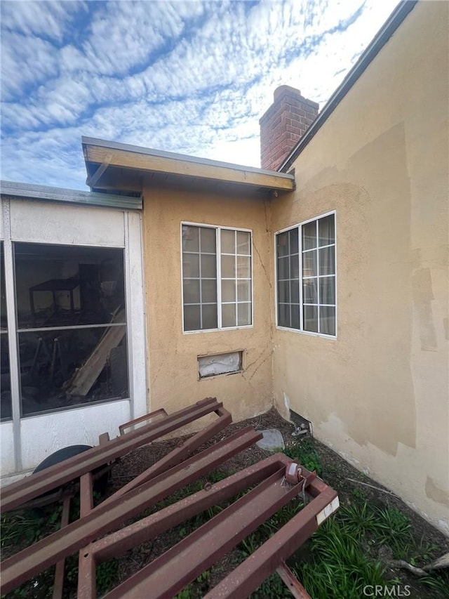 view of property exterior with a chimney and stucco siding