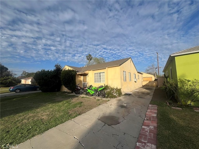 view of property exterior featuring a yard, fence, driveway, and stucco siding