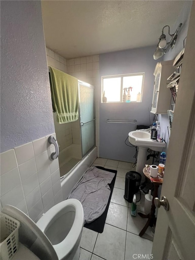 bathroom featuring a textured wall, toilet, a shower stall, a textured ceiling, and tile patterned flooring