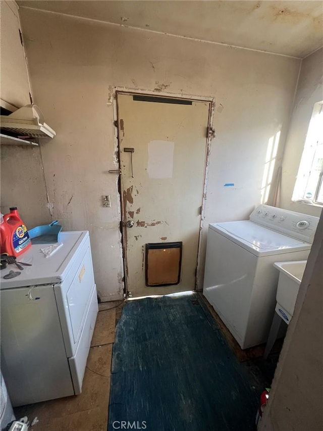 washroom featuring laundry area, light tile patterned flooring, a sink, and washing machine and clothes dryer