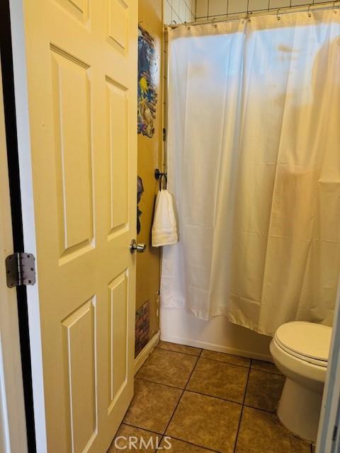 bathroom with toilet, tile patterned flooring, and shower / bathtub combination with curtain