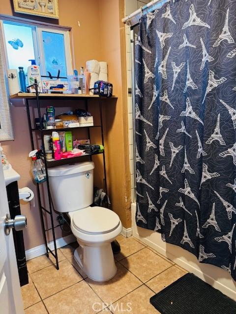 full bathroom with baseboards, shower / tub combo with curtain, toilet, and tile patterned floors