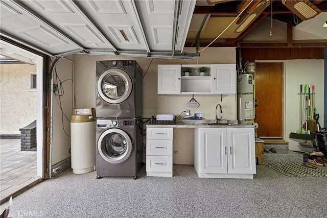 clothes washing area with water heater, stacked washer and dryer, cabinet space, and a sink
