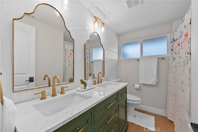 bathroom featuring toilet, visible vents, a sink, and wood finished floors