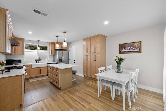 kitchen with visible vents, appliances with stainless steel finishes, a sink, baseboards, and light wood-style flooring