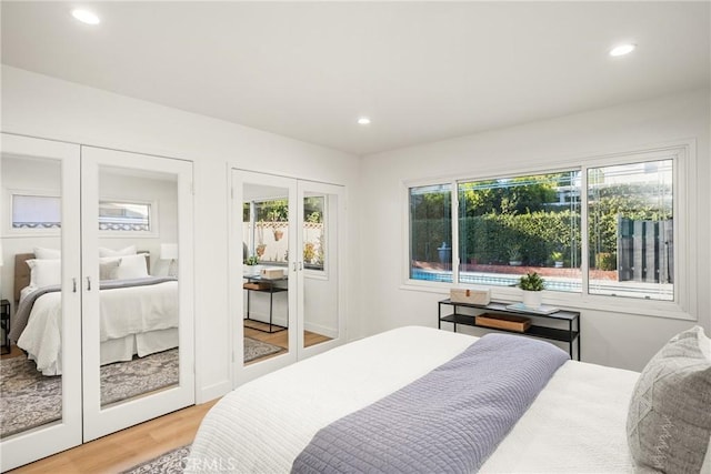 bedroom featuring recessed lighting, light wood-style flooring, french doors, and two closets