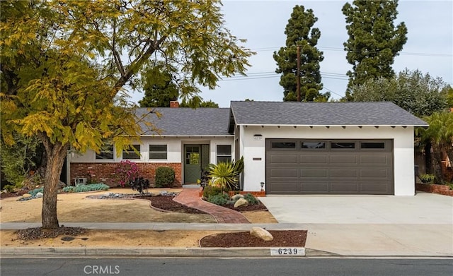 ranch-style home featuring a garage, brick siding, driveway, and stucco siding