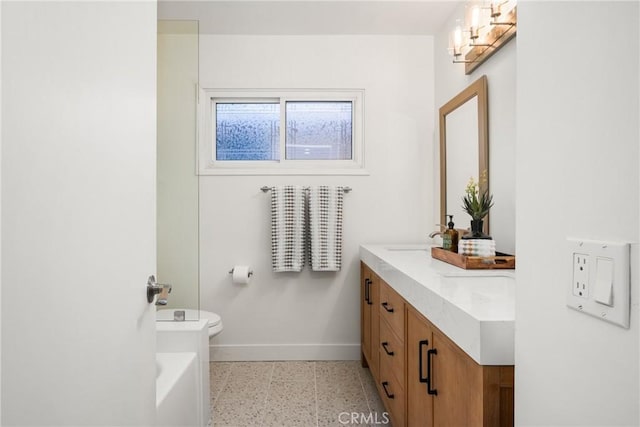 full bathroom with double vanity, toilet, baseboards, and a sink