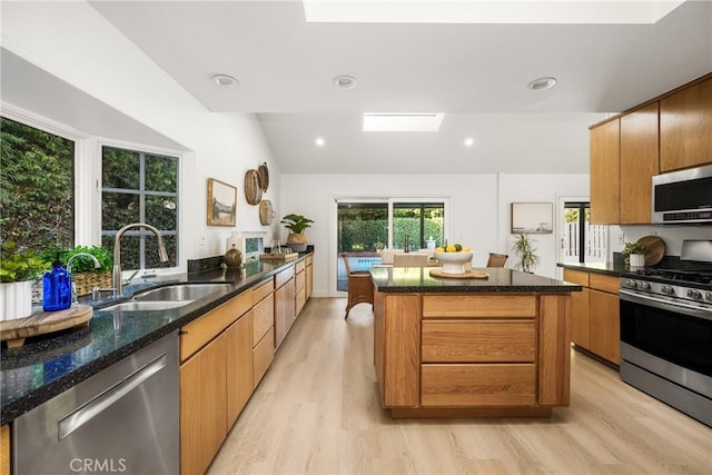 kitchen featuring a wealth of natural light, a sink, dark stone countertops, a center island, and stainless steel appliances