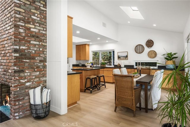 dining space featuring visible vents, light wood finished floors, a skylight, recessed lighting, and a fireplace