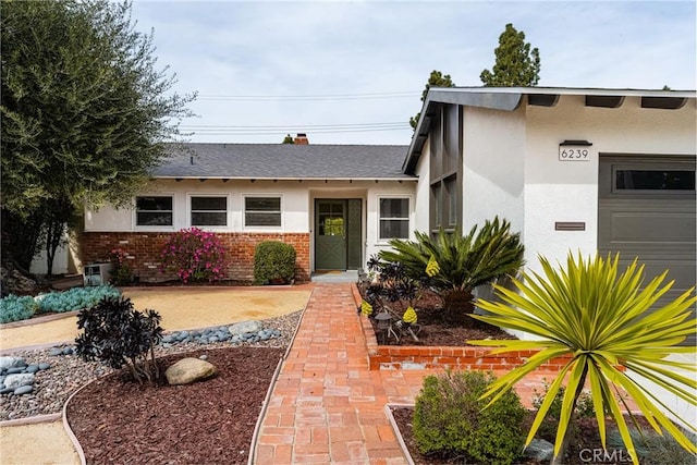 6239 E 6th St, Long Beach, CA 90803 - view of front facade featuring stucco siding, brick siding, an attached garage, and roof with shingles
