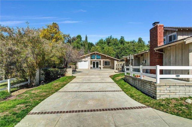 view of property's community with a garage, fence, and concrete driveway