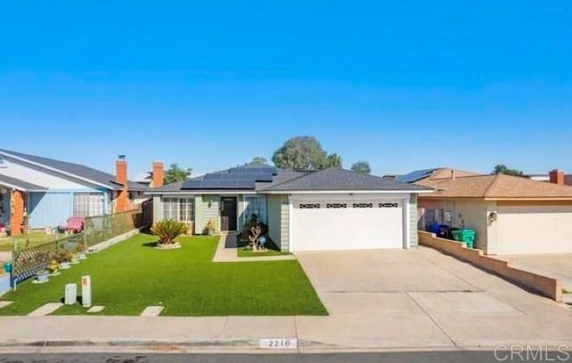 ranch-style home featuring solar panels, fence, a garage, driveway, and a front lawn