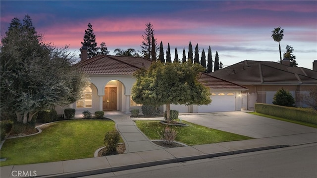 view of front facade featuring an attached garage, a tile roof, concrete driveway, stucco siding, and a front yard